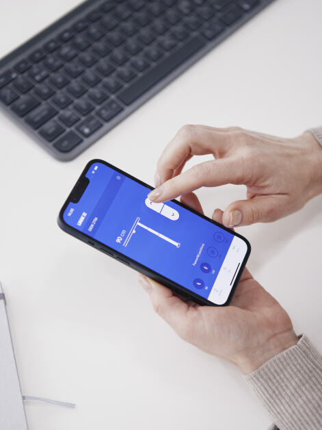 A woman using the LINAK mobile app to remotely adjust the height of the ATS table by Faust.