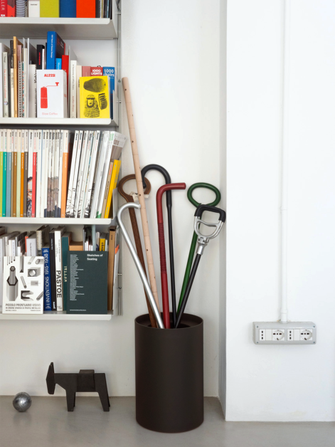 One TIDY Paper Bin by Keiji Takeuchi in Charcoal linoleum containing many walking sticks next to a bookshelf in Keiji’s Milanese studio