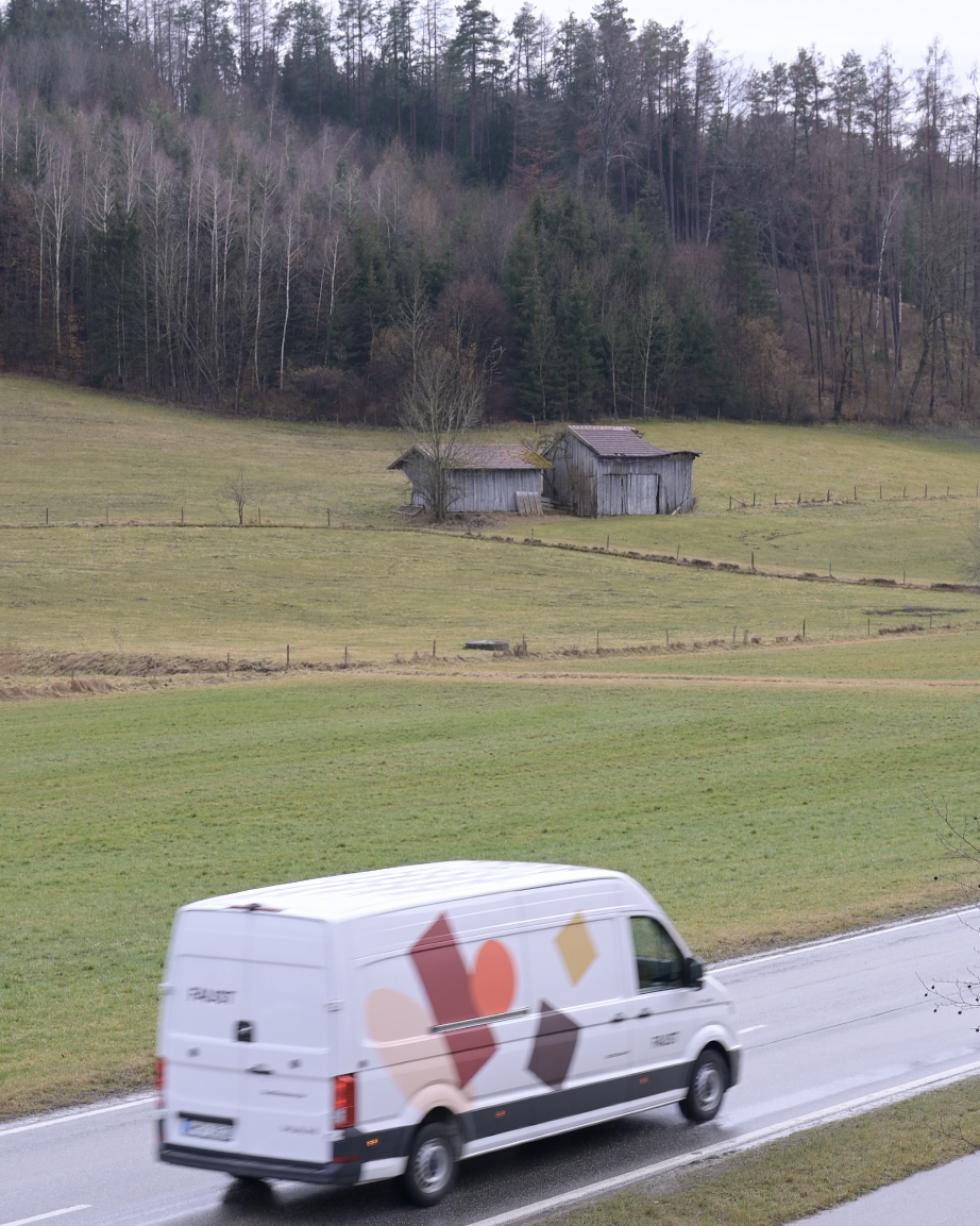 Transporter mit Faust-Beklebung fährt auf Landstraße bei Huglfing – unterwegs zur Auslieferung von Möbeln in ländlicher Umgebung.