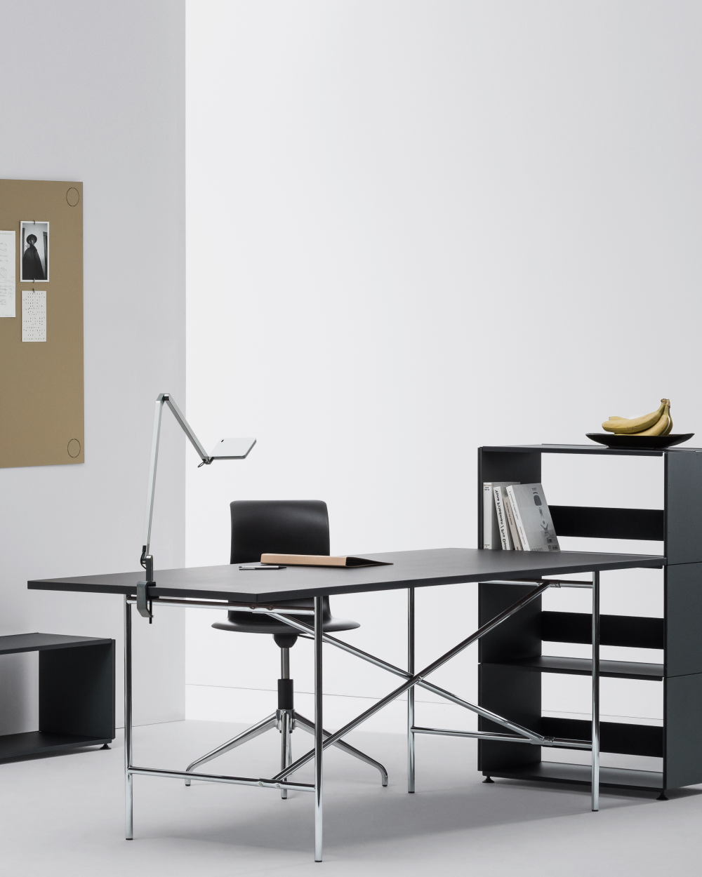 E2 desk with black linoleum top in a modern office, combined with a shelf, chair, and wall board.