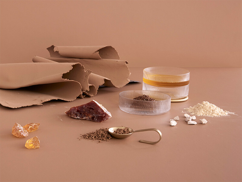 Übersicht natürlicher Linoleum-Rohstoffe: Leinöl, Harz, Holzmehl, Pigmente, Kalkstein und Granulat – arrangiert als Materialstudie für Faust.