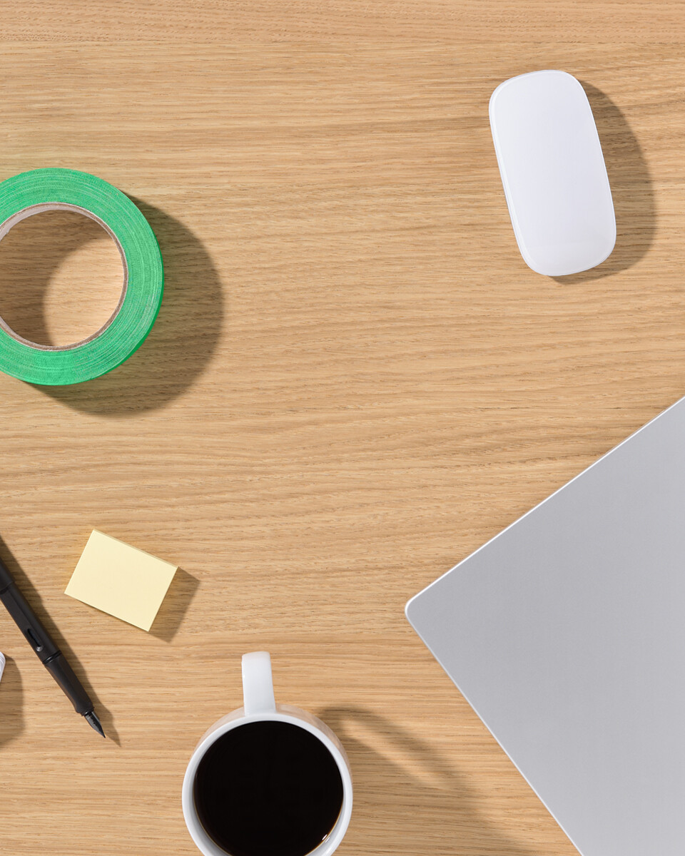 Eichefurnier-Tischplatte von Faust mit Laptop, Kaffeetasse, Farbfächer, Stift und Klebeband – Aufsicht auf einen Arbeitsplatz.