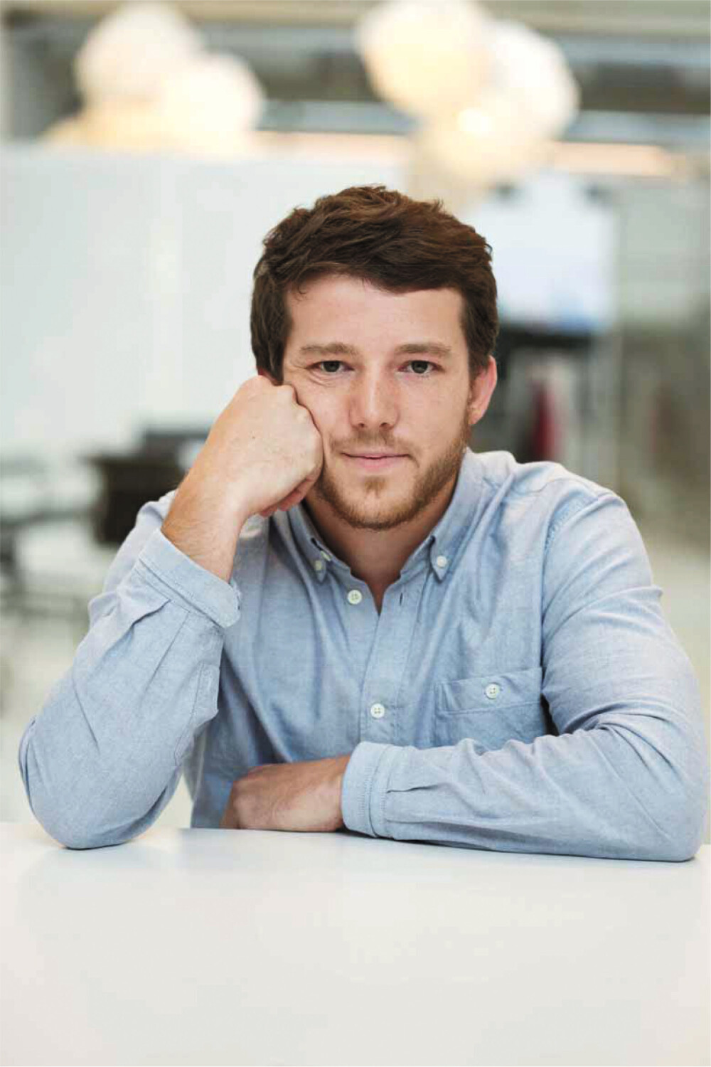 Michel Charlot, Schweizer Industriedesigner – im Porträt für Faust, sitzend am Tisch, mit hellem Hemd und direktem Kamerablick.