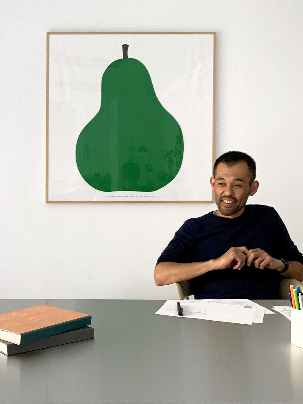 Porträt von Keiji Takeuchi in seinem Mailänder Studio – sitzend an einem Arbeitstisch mit Unterlagen, fotografiert für Faust.