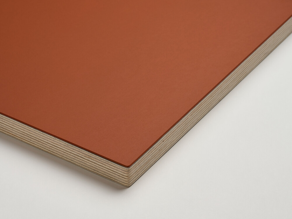 Corner view of a Faust table top with matt linoleum surface in terracotta and 2.9 cm thick multiplex edge made of solid birch.