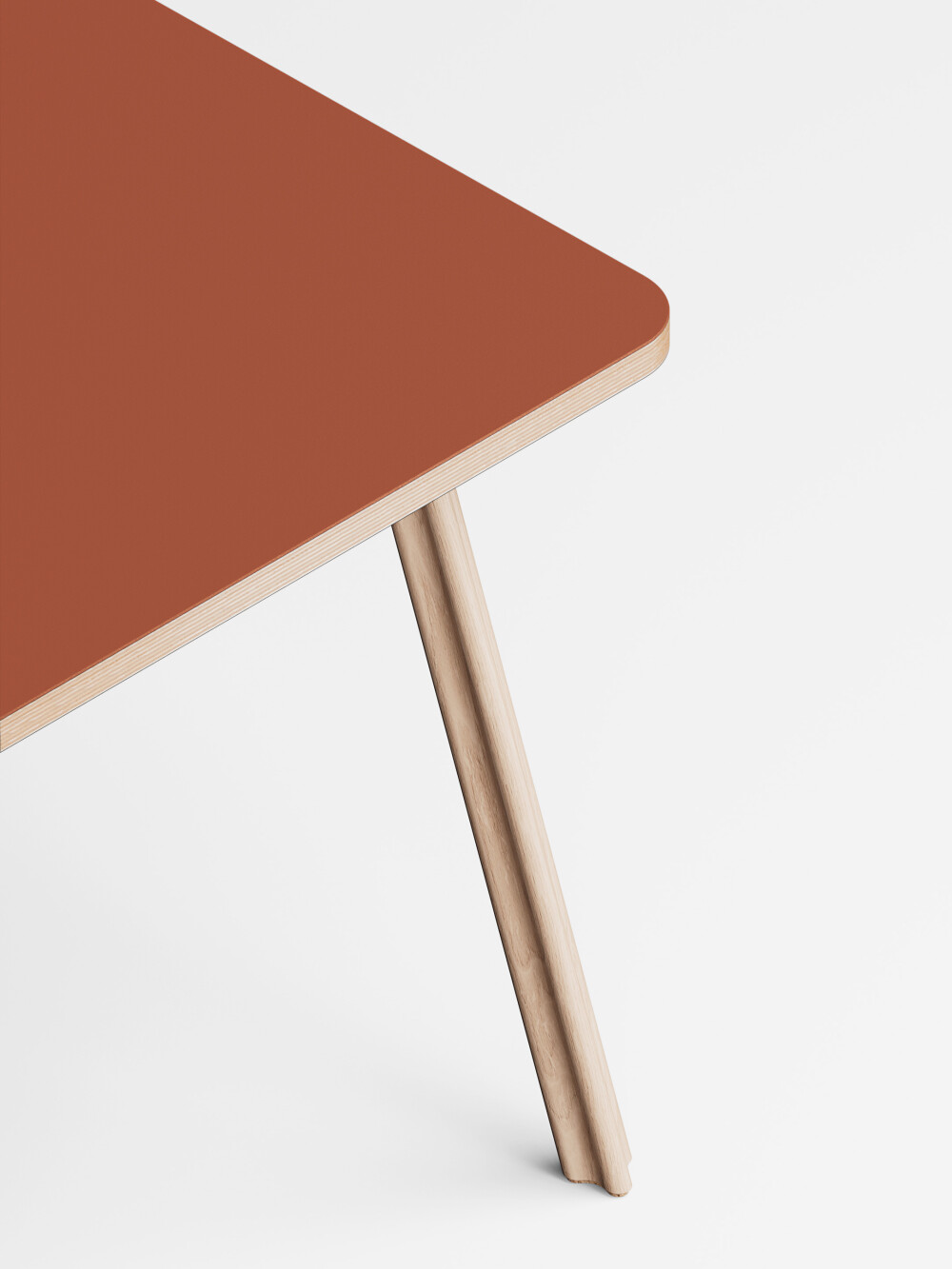 Detailaufnahme des Beam Tischbeins aus massiven Eschenholz mit Korkfüßen an einer blauen Linoleum Tischplatte.