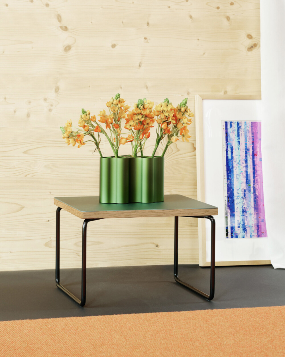 Low & Lower side table by Faust with dark green linoleum and black frame, decorated with a green vase and flowers.