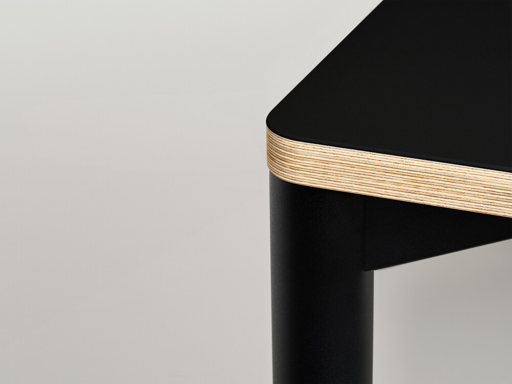 Detail view of the Outline tabletop by Faust with black Nero linoleum surface and visible plywood edge.