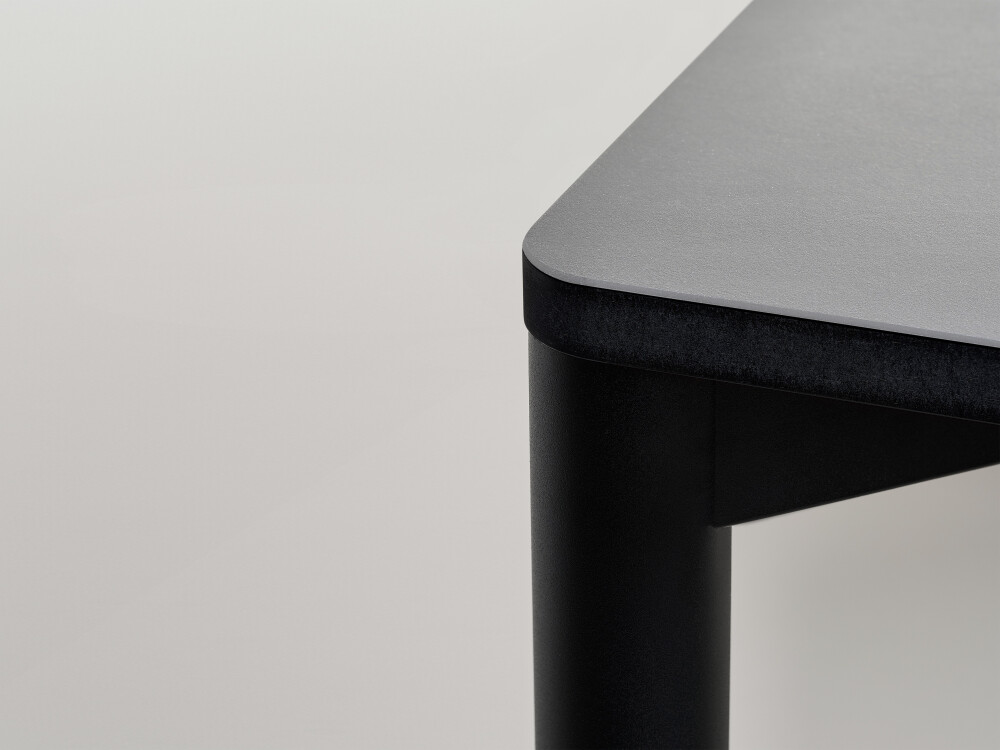 Detail view of the Outline tabletop by Faust with grey linoleum surface and black MDF edge.