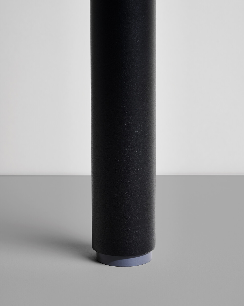 Detail view of an Outline table leg by Faust with rubber adjustable height glide for stability on various floor surfaces.